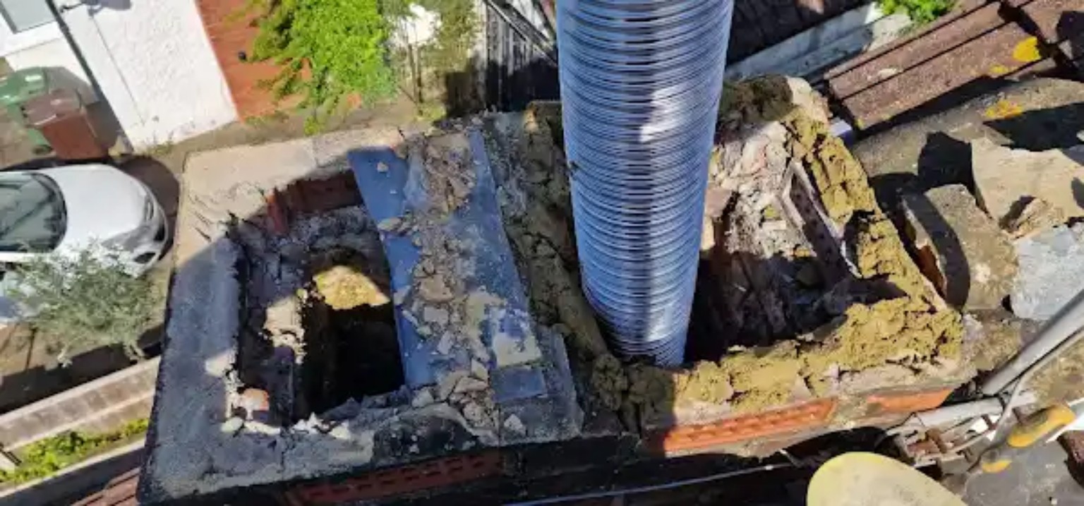 Chimney stack opened up at roof level with new flexible flue liner being installed