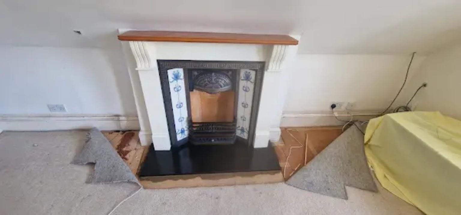 Finished traditional fireplace with decorative cast iron insert, blue patterned tiles and black hearth